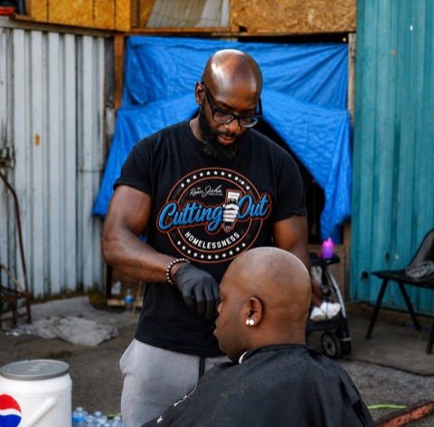 Volunteer barber cutting a client's hair outdoors