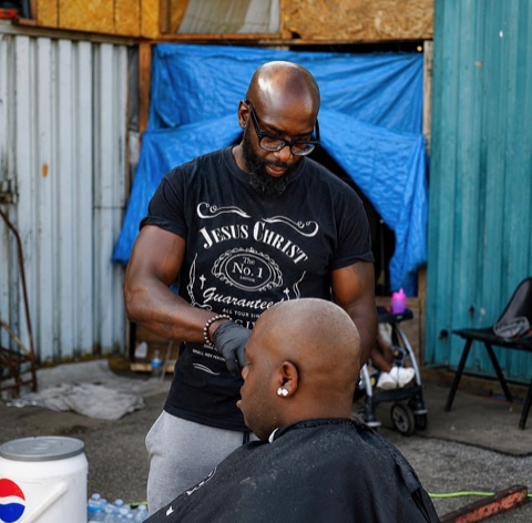 Volunteer barber cutting a client's hair at an outdoor event
